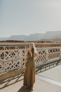 a woman in a green dress standing on a bridge