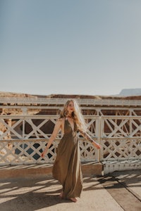 a woman in a green dress standing on a bridge