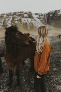 a woman petting a horse in iceland