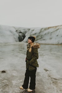 a woman standing in front of a glacier in iceland