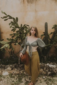 a woman is standing in front of a cactus