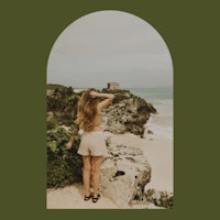 a woman is standing on a cliff overlooking the ocean