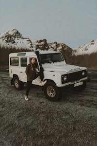 a woman standing in front of a white land rover